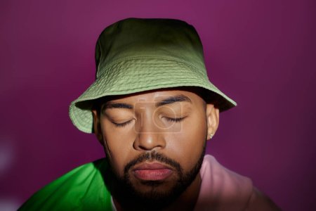 Photo for Close up young man in green panama with purple sweatshirt tied on shoulders, closed eyes, fashion - Royalty Free Image