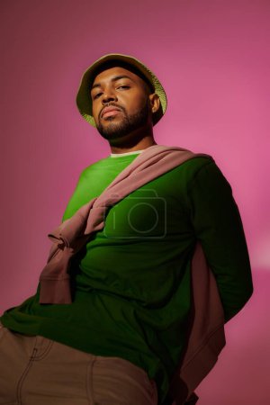 hombre afroamericano guapo en panama verde con barba mirando a la cámara, concepto de moda