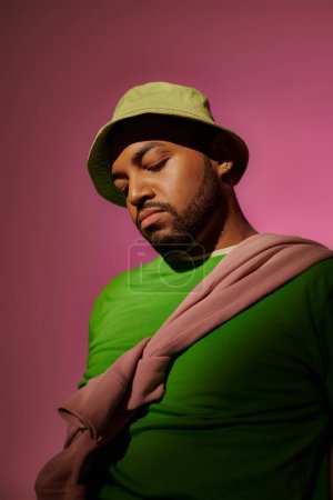 good looking male model with beard and diamond earring posing on pink backdrop, fashion concept
