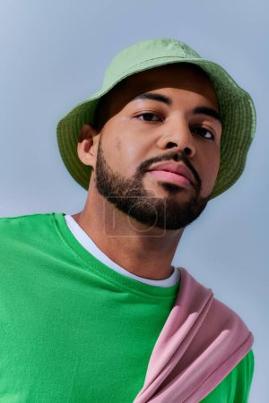 portrait of young handsome man with beard in green panama looking at camera, fashion concept