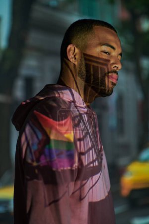 trendiges afrikanisch-amerikanisches Männermodel posiert im Profil in digitalen Projektorleuchten, Modekonzept
