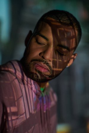 portrait of young stylish man with beard looking away in digital projector lights, fashion concept