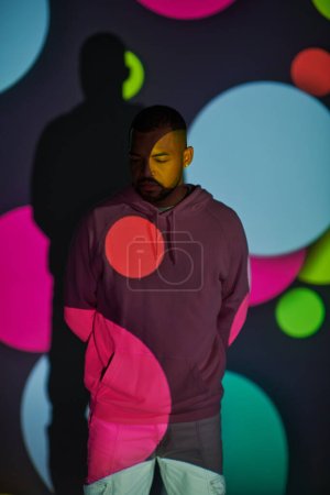 good looking bearded man with hands behind his back in digital projector lights, fashion concept