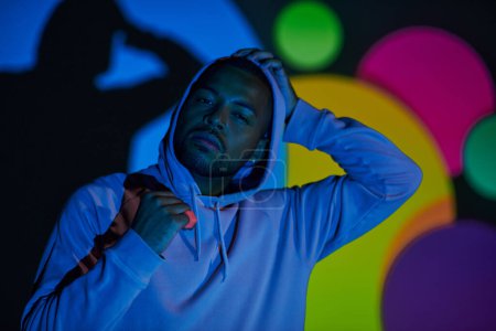 Photo for Portrait of young man with hood on looking at camera in digital projector lights, fashion concept - Royalty Free Image