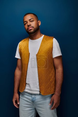young african american male model with beard and earring in trendy yellow vest, fashion concept