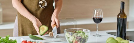 cropped banner, woman cutting ripe avocado near fresh ingredients and red wine, home cooking