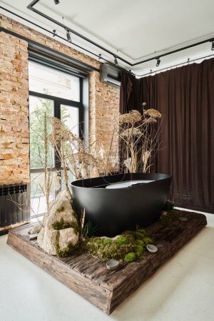 black bathtub inside of modern apartment with panoramic windows and decorative plants and mold
