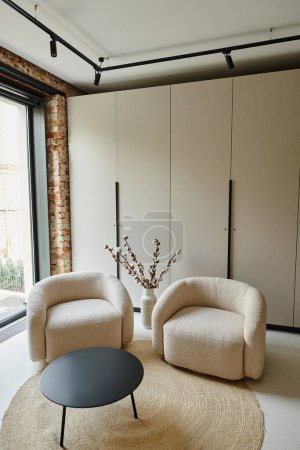 dwa wygodne fotele obok czarnego stolika i bawełniane gałęzie w wazonie, nowoczesny salon