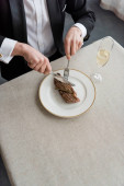 top view of wealthy man in tuxedo cutting delicious beef steak on plate near glass of champagne puzzle #675984386