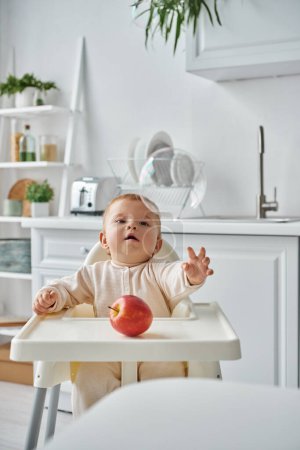Sorglosigkeit Kind sitzt im Babystuhl neben Apfel und schaut auf fliegende Seifenblase, frohen Morgen