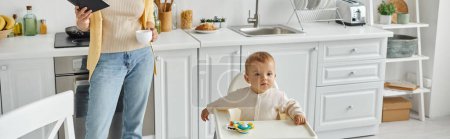 niña sentada en silla de bebé cerca de juguete sonajero cerca de mamá con portátil y taza de café, pancarta