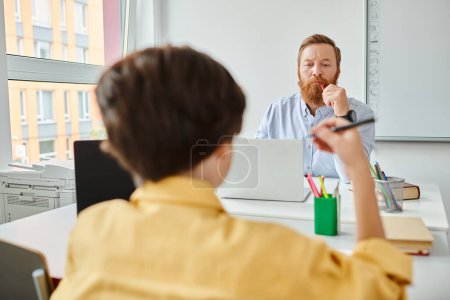 Ein Mann sitzt gelassen an seinem Schreibtisch, das Leuchten des Computerbildschirms und schaut den Jungen an