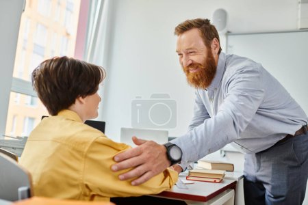 Un homme dans une salle de classe encourageant le garçon, symbolisant le mentorat, l'orientation et un lien positif.