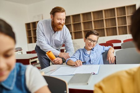 Un homme se tient à côté d'un garçon dans une salle de classe colorée, s'engageant dans l'apprentissage dynamique et l'enseignement.
