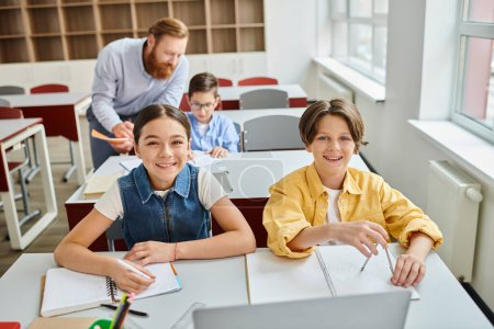 Photo for A group of children attentively sit at desks, listening to a male teachers instructions in a bright and lively classroom setting. - Royalty Free Image