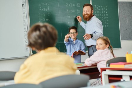 Ein männlicher Lehrer steht selbstbewusst vor einer Tafel und unterrichtet eine Gruppe von Kindern in einem hellen und lebendigen Klassenzimmer..