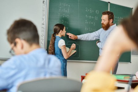 Ein engagierter Lehrer steht vor einem lebhaften Klassenzimmer und unterrichtet eine Gruppe von Kindern vor einer Tafel.