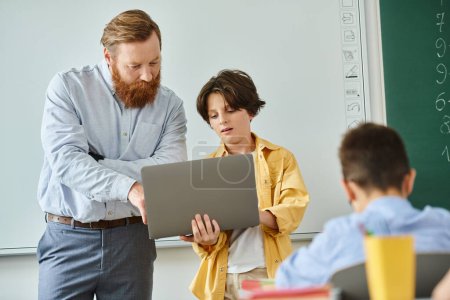 A man stands confidently in front of a laptop, teaching a group of kids. The bright classroom setting adds to the lively atmosphere.