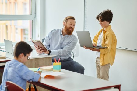Téléchargez les photos : Un homme est assis à un bureau, concentré sur un écran d'ordinateur portable devant lui à côté des enfants - en image libre de droit
