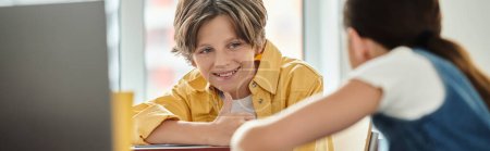 Téléchargez les photos : Kids at a desk engaged in conversation with each other in a colorful classroom setting. - en image libre de droit