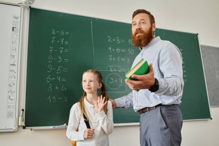 A man in casual clothing stands beside a little girl, both looking attentively at a blackboard full of equations and diagrams.