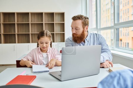 Ein Mann und ein kleines Mädchen sitzen aufmerksam vor einem Laptop und beschäftigen sich während einer lebhaften Unterrichtsstunde mit Unterrichtsinhalten..