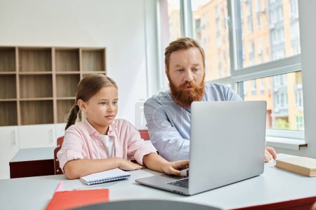 A man and a little girl sitting in front of a laptop, engrossed in a learning activity. The man appears to be teaching and guiding the girl while she attentively listens.