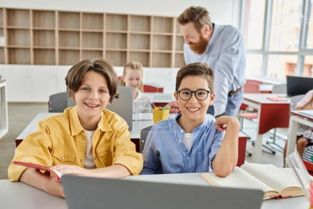 Un couple d'enfants attentivement engagés avec un ordinateur portable, explorant et apprenant sous la direction de leur professeur dans un cadre de classe lumineux et animé.