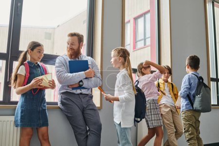 Photo for A group of young people standing in unity, listening to their male teacher in a bright, lively classroom setting. - Royalty Free Image