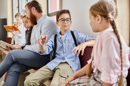 Un maestro masculino instruye a un grupo de niños diversos en un ambiente brillante y animado en el aula, sentados uno al lado del otro y absortos en el aprendizaje.