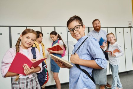 Photo for A diverse group of children, guided by their male teacher, stand attentively in a bright hallway, ready to embark on a new learning adventure. - Royalty Free Image