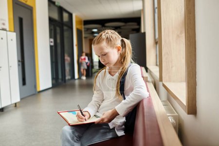 Photo for A young girl with thoughtful expression sitting on a wooden bench, focusing on writing in a notebook. - Royalty Free Image