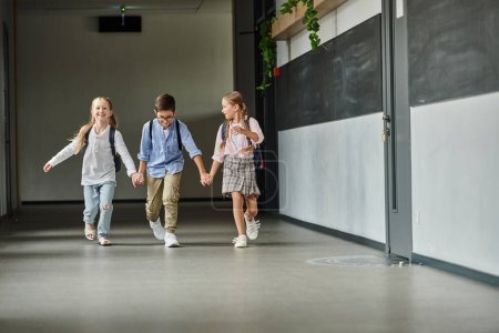 A group of children, walking down a brightly lit hallway in a school.