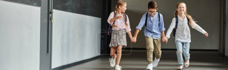 Photo for A group of young students, confidently strides down a brightly lit school hallway. - Royalty Free Image