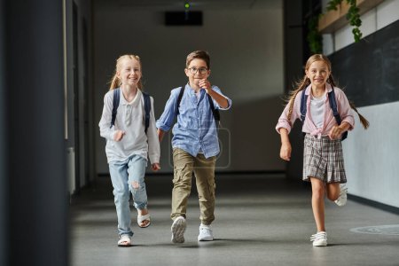 group of young children joyfully walking down a bright hallway