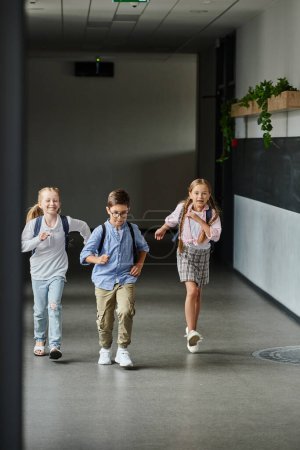 A group of young children laughing and running through a hallway, filled with excitement and energy.