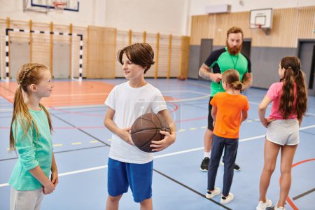 Eine bunte Gruppe junger Leute steht um einen Basketballplatz herum, plaudert und lacht, während ein männlicher Lehrer sie in einem lebhaften Rahmen unterrichtet..