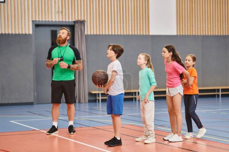 Ein Mann steht vor einer Gruppe von Kindern, hält einen Basketball in der Hand und gibt Anleitung in einem lebhaften, engagierten Klassenzimmer.