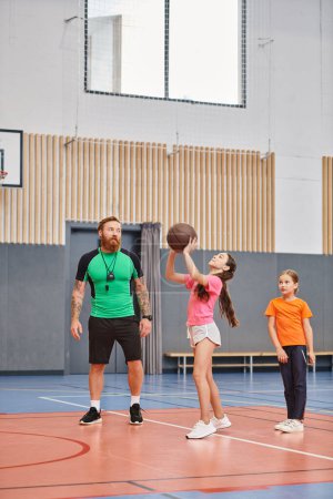 A man, showing basketball techniques, plays with children in a gym filled with energy and excitement.