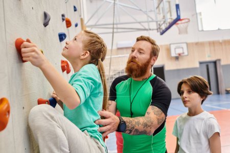 A man, acting as a teacher, leads two children in climbing up a wall in a bright and lively classroom setting.