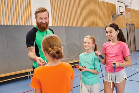 Diverse group of people, including kids and a teacher, standing attentively around each other in a lively gym, the teacher instructing with enthusiasm.