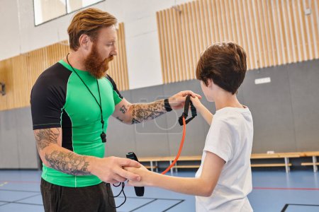 A tattooed man teaches a young boy how to hold a jump rope in a vibrant classroom setting.