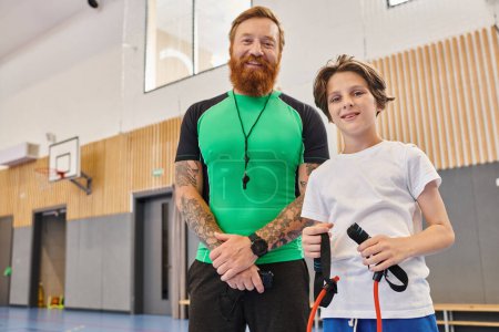 A man stands next to a boy in a gym, engaging in physical activities and fitness training together.