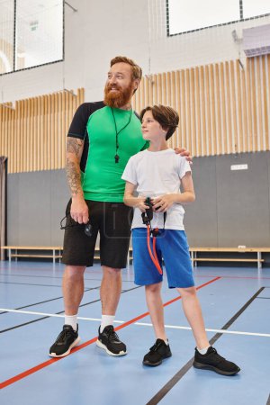 Foto de El hombre está instruyendo al niño en una cancha de baloncesto, mostrando los fundamentos del juego de una manera comprensiva y atractiva. - Imagen libre de derechos