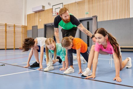 A diverse group of kids are engaging in a synchronized session of push ups on a gym floor, guided by their instructor.