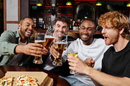 group of happy interracial male friends toasting glasses of beer in bar, men during bachelor party