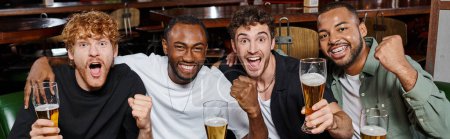Téléchargez les photos : Bannière des amis excités interracial acclamant avec des verres de bière dans le bar, les hommes sur enterrement de vie de garçon - en image libre de droit