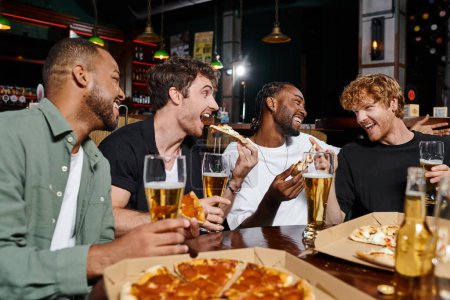 group of four happy interracial friends eating pizza and drinking beer in bar, men on bachelor party