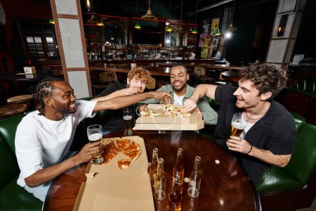 grupo de cuatro amigos multiétnicos que comparten pizza y beben cerveza en el bar, hombres en despedida de soltero