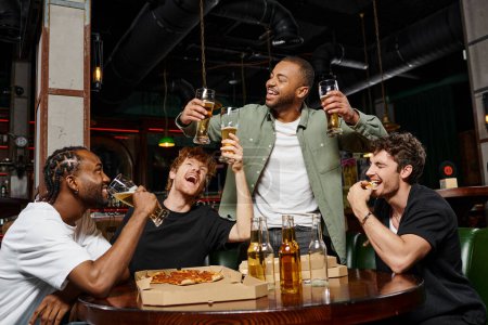 happy african american man raising two glasses of beer near friends during bachelor party in bar